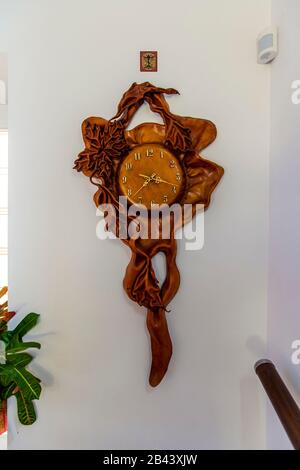 Horloge sur le mur dans un cadre en acajou avec des ornements floraux sculptés en bois. Banque D'Images