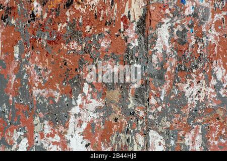 Mur avec des traces de vieille peinture écaillée, papier déchiré et fond de colle. Texture d'un mur de rue sale avec des annonces et des affiches déchirées. Banque D'Images