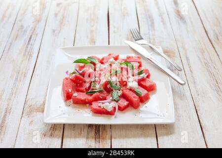 Salade de pastèques fraîches avec fromage feta et menthe sur une assiette blanche Banque D'Images