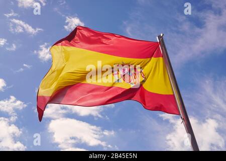 Drapeau de l'Espagne agitant dans le vent devant un ciel bleu ensoleillé avec des nuages. Drapeau espagnol en haute résolution, concept de voyage et de tourisme. Banque D'Images