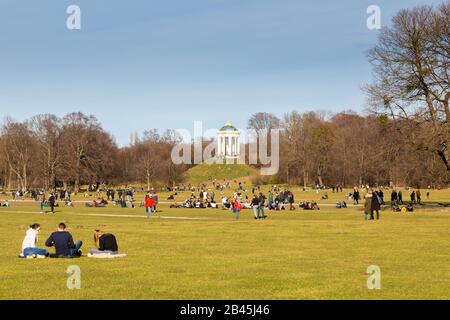 Vue sur le Monopteros du jardin anglais (Englischer Garten). Au premier plan, les gens marchent et s'assèturent dans l'herbe. Parc populaire. Banque D'Images