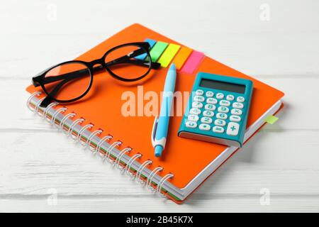 Copybook, lunettes, calculatrice, stylo et autocollants sur fond en bois, gros plan Banque D'Images