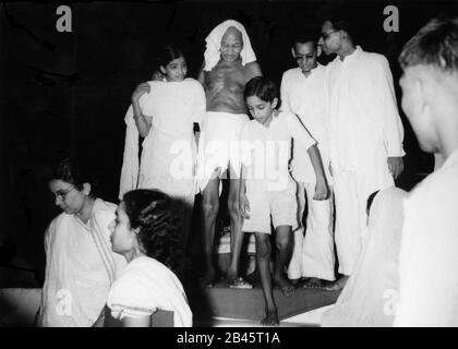 Mahatma Gandhi marchant avec le soutien des enfants pendant son séjour à Calcutta, Bengale-Occidental, Inde, Asie, 1947, ancienne image millésime 1900 Banque D'Images