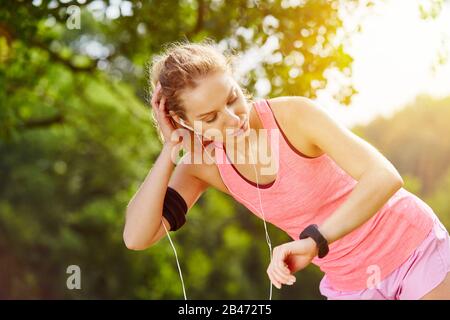 Femme jogging regarde la montre intelligente pour mesurer le pouls et la fréquence cardiaque Banque D'Images