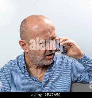 Un homme d'âge moyen fait valoir au cours d'une conversation avec un téléphone portable Banque D'Images