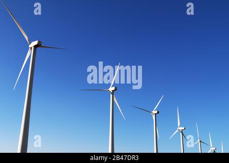 des éoliennes blanches brillantes à rangées diagonales et un ciel bleu vif Banque D'Images