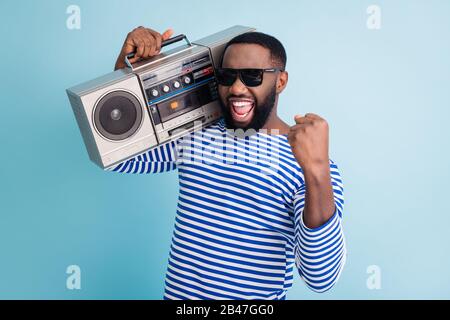 Photo d'un drôle de peau sombre gars tenir rétro cassette enregistreur sur l'épaule lever poing incroyable étudiants fête froid porter soleil lunettes de soleil rayé marin chemise Banque D'Images