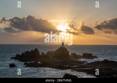 Phare de Corbiere avec poutres apparentes en streaming dans les nuages. Jersey, îles Anglo-Normandes Banque D'Images