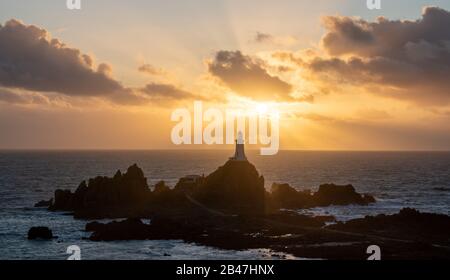 Phare de Corbiere avec poutres apparentes en streaming dans les nuages. Jersey, îles Anglo-Normandes Banque D'Images