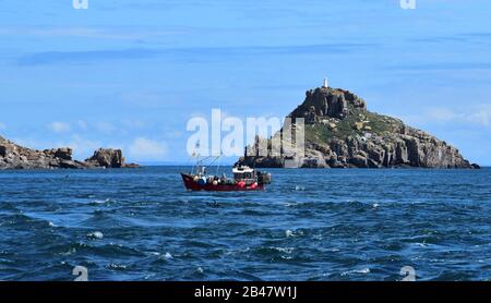 Bateau de pêche et monument dans la Manche au large de Guernesey Banque D'Images