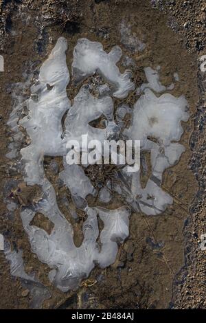 Flaque surgelée avec bulles d'air sur une route de terre en hiver Banque D'Images