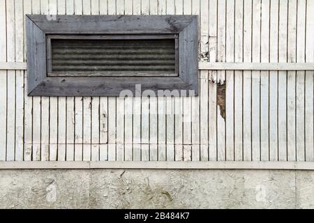 une petite longue fenêtre à bord sur un mur blanc de grange pâle Banque D'Images