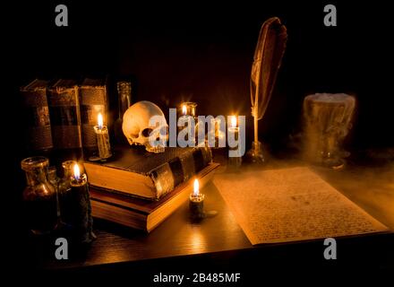 Bureau de l'assistant éclairé par une bougie. Crâne humain, vieux livres, un goblet, potion bouteilles. Le brouillard s'écoule du goblet au papier parchemin avec de l'écriture en arcane. Banque D'Images