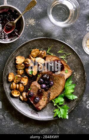 Boeuf mijotés avec champignons et sauce aux bleuets sur pierre sombre arrière-plan. La viande en ragoût savoureux avec champignons et sauce douce. Haut de la vue, télévision lay Banque D'Images