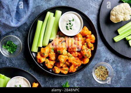 Gros plan des ailes de buffle de chou-fleur avec céleri et sauce sur la plaque sur fond de pierre bleue. Alimentation saine, concept de nourriture à base de plantes. Vue de dessus, f Banque D'Images