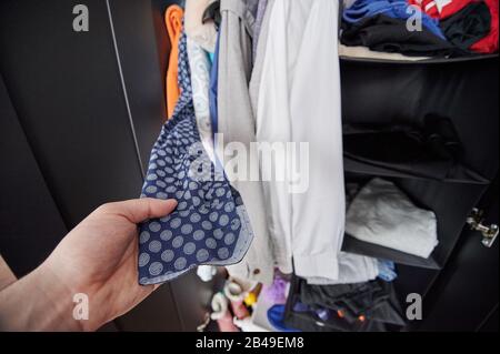 Homme choisissant une chemise dans la garde-robe complète dans la chambre d'appartement Banque D'Images