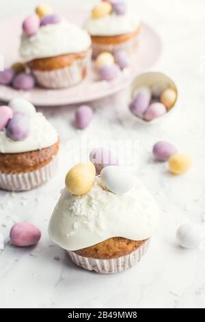 Cupcakes de Pâques glacés décorés de mini œufs au chocolat sur fond de marbre blanc. Joyeuses Vacances De Pâques. Banque D'Images
