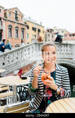 Jeune voyageur de sexe féminin profitant d'un verre d'spitz dans un café en plein air à Venise, en Italie Banque D'Images