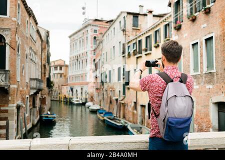 Jeune voyageur prenant une photo avec son smartphone d'un canal à Venise, Italie Banque D'Images