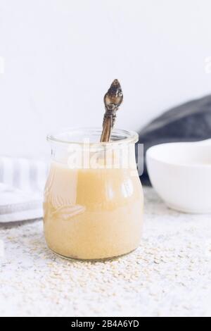 Tahini maison ou tahina, coller de la masse des graines de sésame. Oriental pâte de graines de sésame dans un bocal en verre. Concept d'aliments biologiques naturels sains. Banque D'Images