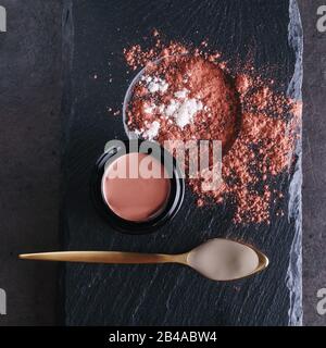 Belle photo de skincare en argile rose produit dans un élégant pot en verre noir ouvert près de la cuillère dorée remplie d'argile blanche crémeuse entourée d'argile sèche s Banque D'Images