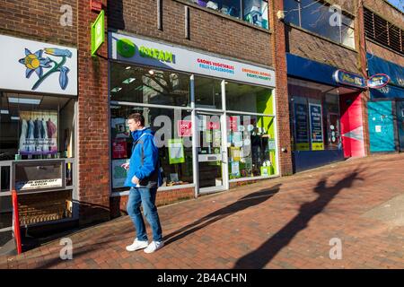 Un homme passe devant la boutique de charité d'Oxfam sur Mount Pleasant Road, Tunbridge Wells, à côté d'une librairie William Hill, Kent, Royaume-Uni Banque D'Images