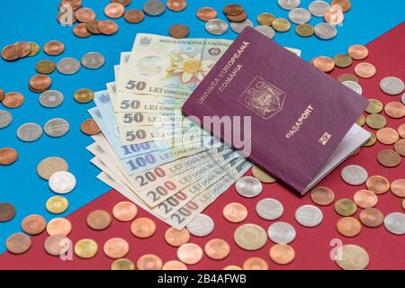 Concept roumain. Le passeport roumain et les billets/pièces roumains sur fond bleu et rouge. Colosse de Passeport roumain et de monnaie roumaine Banque D'Images