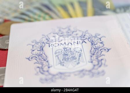 Concept roumain. Le passeport roumain et les billets/pièces roumains sur fond bleu et rouge. Colosse de Passeport roumain et de monnaie roumaine Banque D'Images