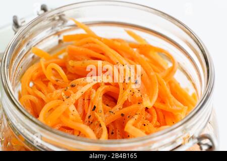 Gros plan de salade de carottes coréennes épicées avec de l'huile, de l'ail et du poivre noir. Emballage durable, fond blanc, haute résolution Banque D'Images