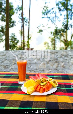 Assiette de fruits. Fruits frais et juteux dans une assiette sur un fond de montagnes. Banque D'Images