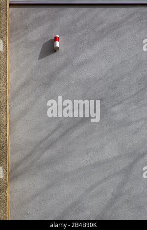 un voyant d'alarme rouge à une façade de béton gris avec des ombres d'un arbre - espace de copie Banque D'Images