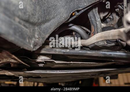 Stabilisateur de direction connecté au porte-fusée de direction, vu du bas de la voiture sur un cric dans l'atelier. Banque D'Images