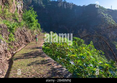 Touriste féminine regardant la vue sur funchal Madeira, Portugal debout sur une levada et avec des montagnes et un ciel bleu en arrière-plan. Banque D'Images