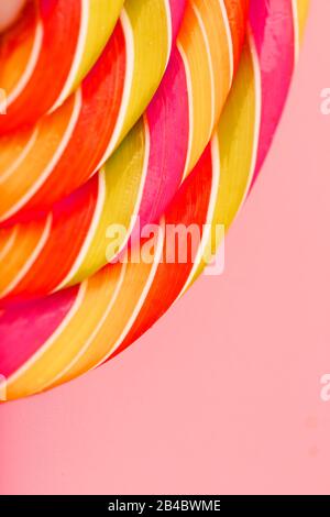 Lollipop multicolore gros plan comme texture d'arrière-plan sur des pièces sur fond rose. Le concept de bonbons sucrés. Banque D'Images