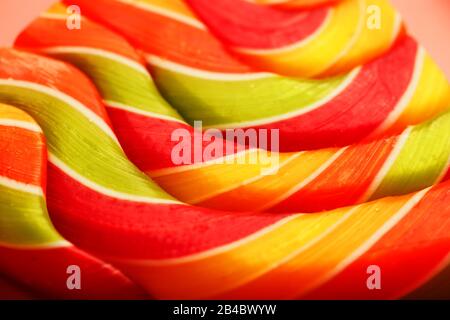 Lollipop multicolore gros plan comme texture d'arrière-plan sur des pièces sur fond rose. Le concept de bonbons sucrés. Banque D'Images