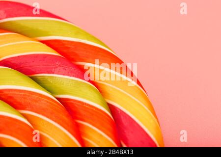 Lollipop multicolore gros plan comme texture d'arrière-plan sur des pièces sur fond rose. Le concept de bonbons sucrés. Banque D'Images