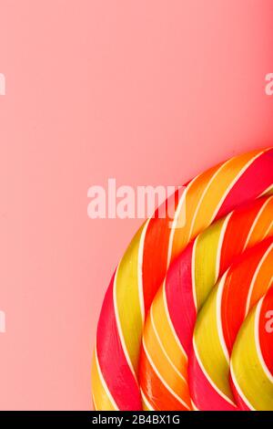 Lollipop multicolore gros plan comme texture d'arrière-plan sur des pièces sur fond rose. Le concept de bonbons sucrés. Banque D'Images