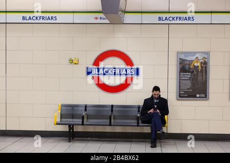 Un homme assis sur un banc sur la plate-forme de la station de métro Blackfriars, ou de la station de métro Blackfriars London, Blackfriars London UK Banque D'Images