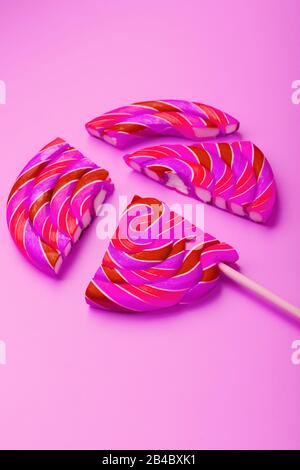 Rose Lollipop divisé en pièces sur un arrière-plan rose, vue du dessus, gros plan. Le concept de la fête douce bonbons. Banque D'Images