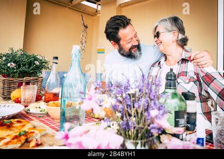 Famille heureuse caucasien personnes couple mère fils senior âge adulte concept avec hug et plaisir entre l'homme et la femme souriant - déjeuner à la maison ou restaurant avec table Banque D'Images