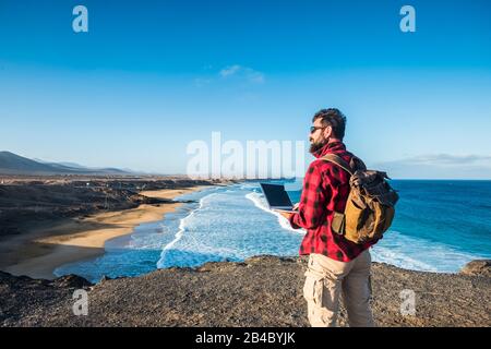 Hipster personnes utilisant l'extérieur cimputer ordinateur portable avec connexion Internet pour le travail ou pour communiquer à la maison - voyageur avec sac à dos et alternative Voyage vacances - plage et mer en arrière-plan Banque D'Images