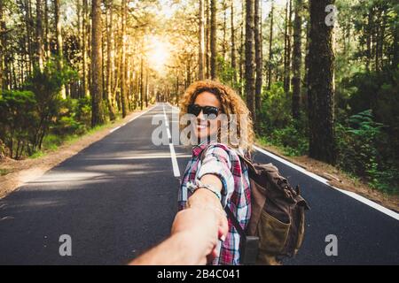 Couple voyageurs Homme et Femme suivez les mains tenant à long chemin route paysage forestier et soleil sur fond Amour et Voyage émotions heureux concept de style de vie. Les gens qui voyagent des vacances d'aventure actives Banque D'Images