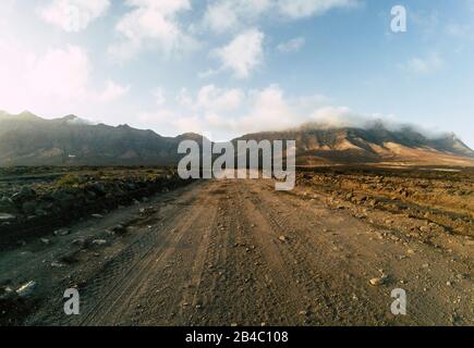 Route tout-terrain vue depuis le niveau du sol avec montagnes et ciel bleu nuageux - concept de voyage et d'aventure pour des vacances et le style de vie alternatifs Banque D'Images