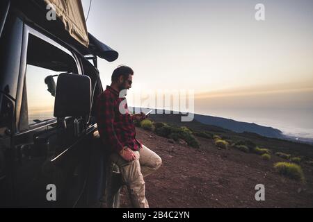 Aventure explorer voyageur homme utiliser le téléphone cellulaire avec connexion Internet dans la nature montagne place pendant l'excursion avec voiture noire hors route et tente sur le toit - concept de personnes gratuit Banque D'Images