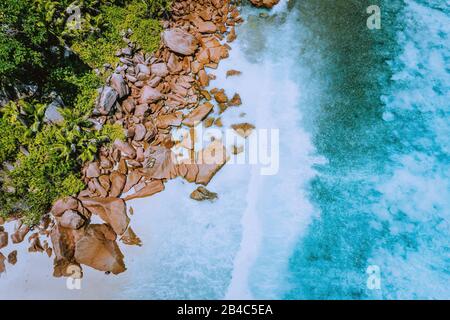 Seychelles La Digue Island. Vue aérienne sur les vagues de l'océan qui frappent d'énormes rochers de granit bizarre sur la plage tropicale anse cocos avec de l'eau turquoise azure. Magnifique paysage de falaises rocheuses sur la côte. Banque D'Images