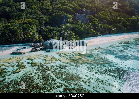 Vue aérienne de la baie avec des eaux peu profondes en début de matinée de la plage tropicale unique d'Anse Source d'argent, la Digue Seychelles. Concept de voyage exotique de luxe. Banque D'Images