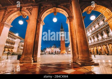 Venise, Italie. Vue panoramique sur la Piazza San Marco encadrées dans des arcs architecturaux après le crépuscule, l'heure bleue. Banque D'Images