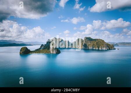 El Nido, Palawan, Philippines. Vue panoramique aérienne bateau touristique solitaire en mer ouverte avec île tropicale exotique de Pinagbuyutan surplombant l'océan. Archipel Basuit D'Asie Du Sud-Est. Banque D'Images