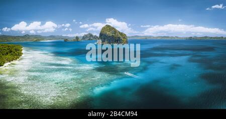 El Nido, Palawan, Philippines. Vue panoramique aérienne bateau touristique solitaire en mer ouverte avec île tropicale exotique de Pinagbuyutan surplombant l'océan. Archipel Basuit D'Asie Du Sud-Est. Banque D'Images