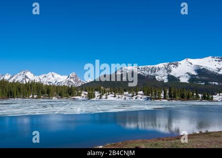 Colorado paysage de glace de fusion sur le lac Molas, avec arbres et montagnes enneigées au loin Banque D'Images